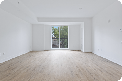 An empty livingroom with white walls and a window and balcony.